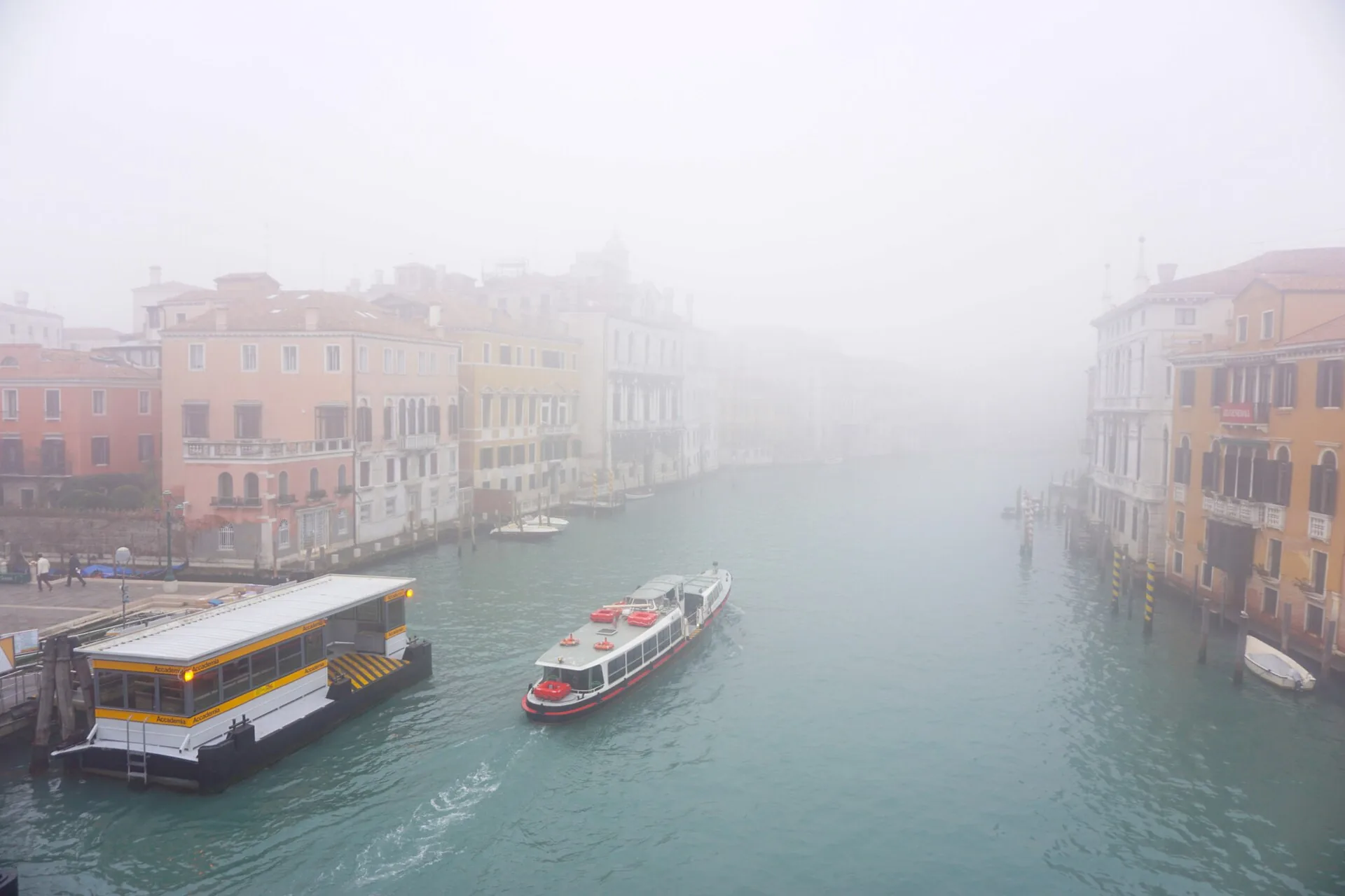 Canale veneziano avvolto dalla nebbia invernale con un vaporetto in transito