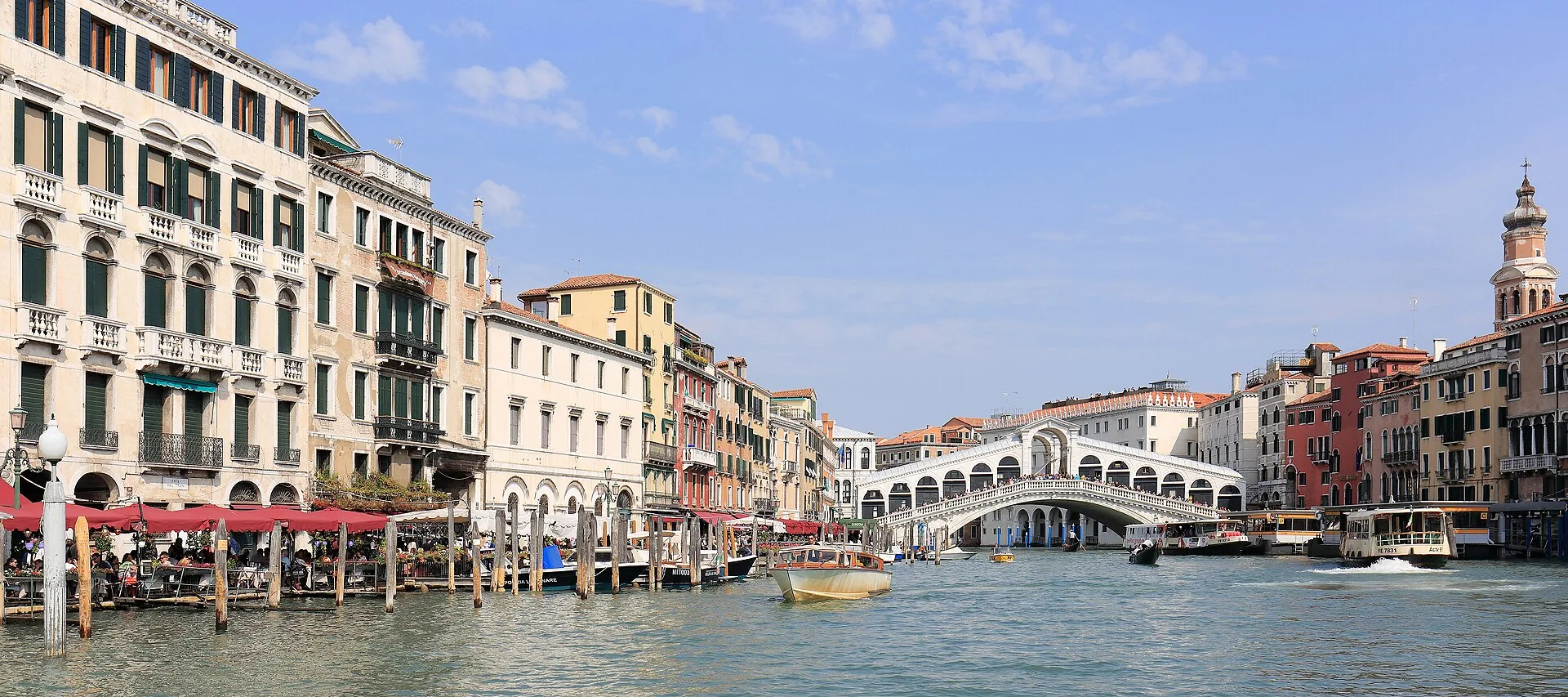 Ponte di Rialto e Canal Grande in una giornata di sole con barche e gondole in transito